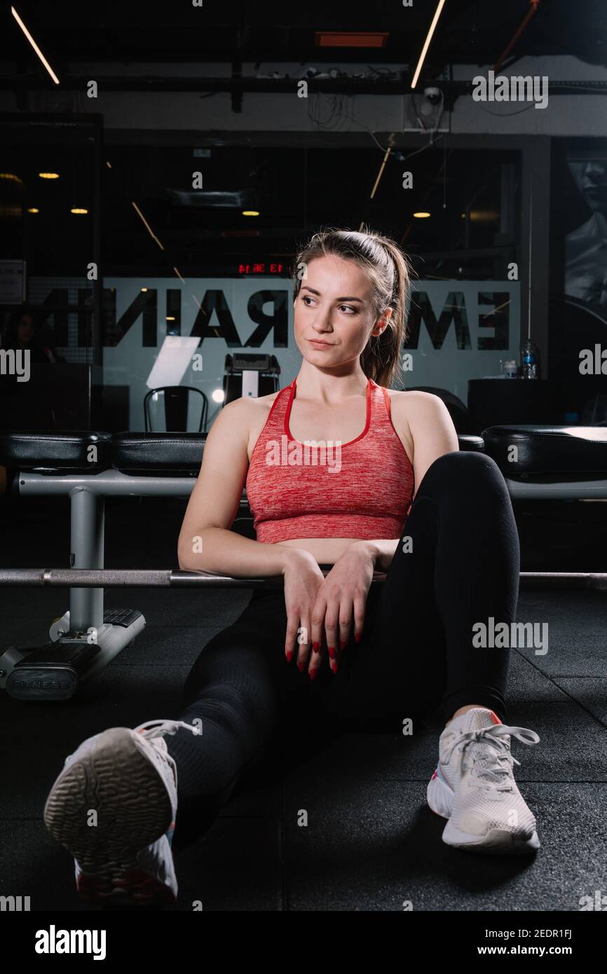 Athletische Frau posiert mit einer Langhantel. Fitness-Mädchen trainieren mit einer Langhantel im Fitnessstudio. Stockfoto