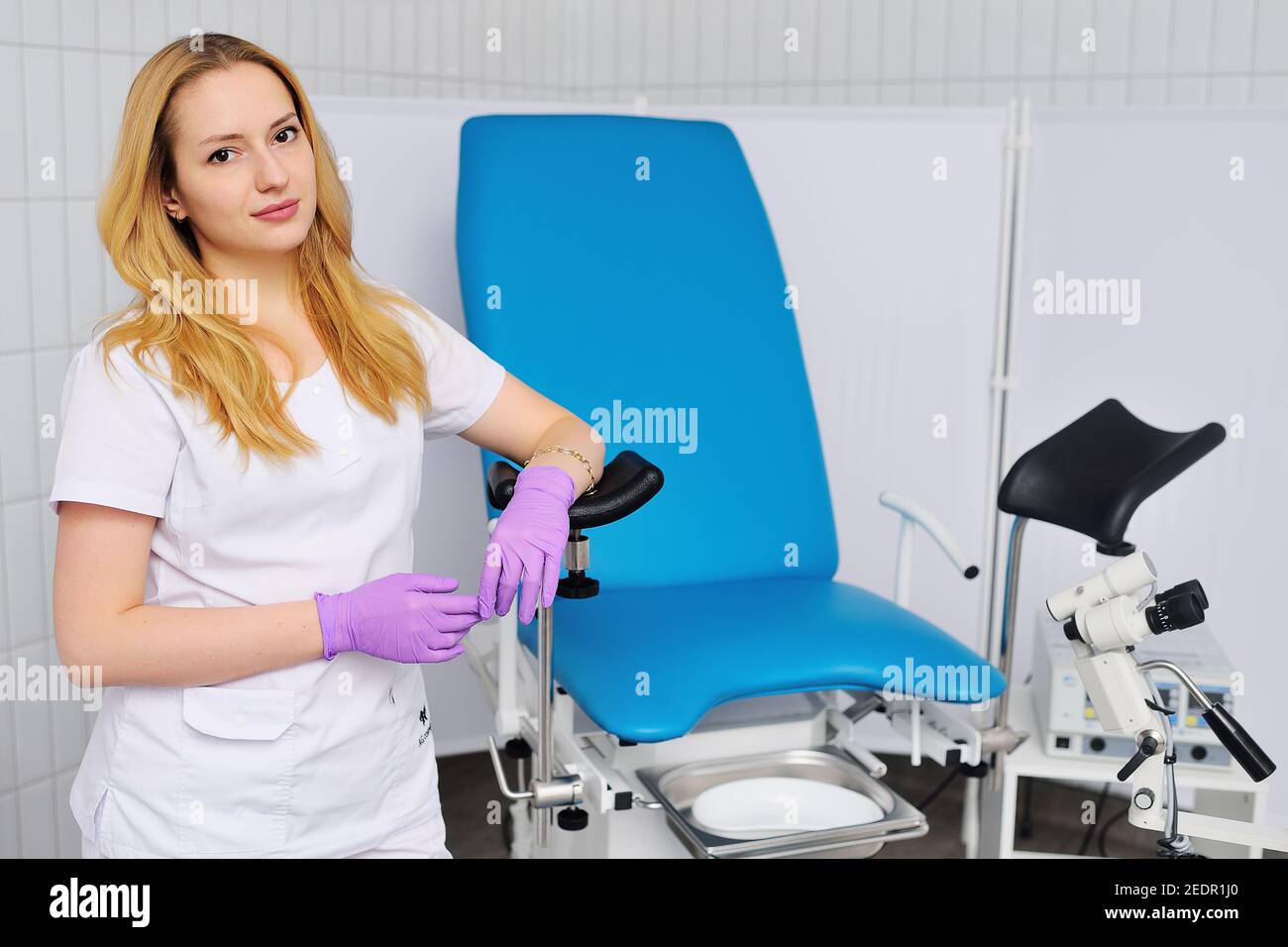 Eine attraktive junge Frau Doktor Gynäkologe auf einem blauen gynäkologischen  Stuhl lehnt lächelt vor dem Hintergrund eines Kolposkopes und einer  modernen Klinik Stockfotografie - Alamy