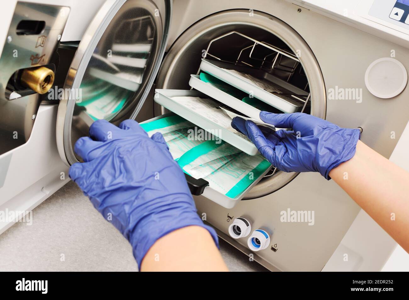 Hände des Arztes in Gummihandschuhen, die sterile Instrumente aus einem Autoklav nehmen. Stockfoto