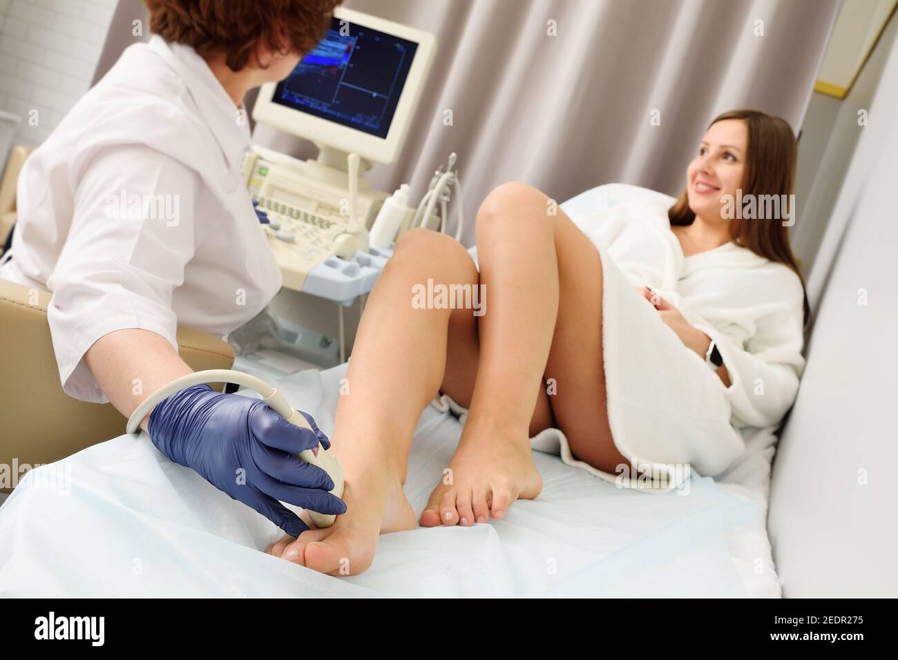 Der Arzt macht einen Ultraschall der Venen und Arterien der unteren Extremitäten. Stockfoto