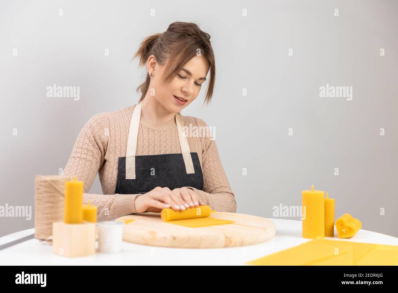 Craft Production Home, Master rollt Bienenwachs Kerzen auf weißem Tisch. Stockfoto