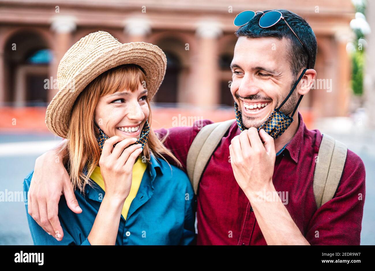 Glückliches Reisepaar lächelnd mit offener Gesichtsmaske - Neu Normales Lifestyle-Konzept mit jungen Menschen auf positive Stimmung nach Wiederöffnung der Sperre Stockfoto