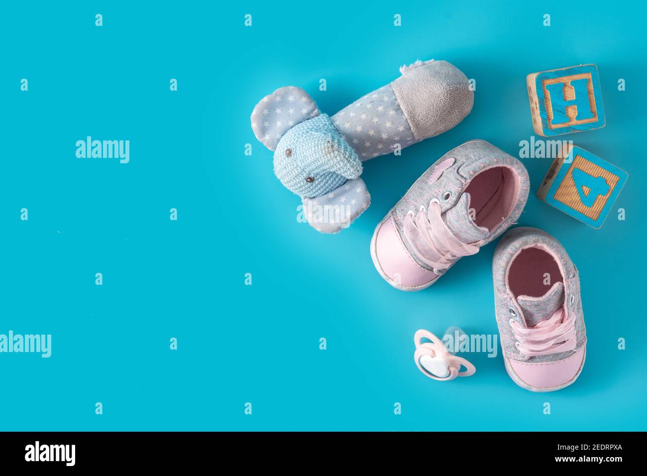 Babyschuhe, Schnuller und Spielzeug auf blauem Hintergrund Stockfoto
