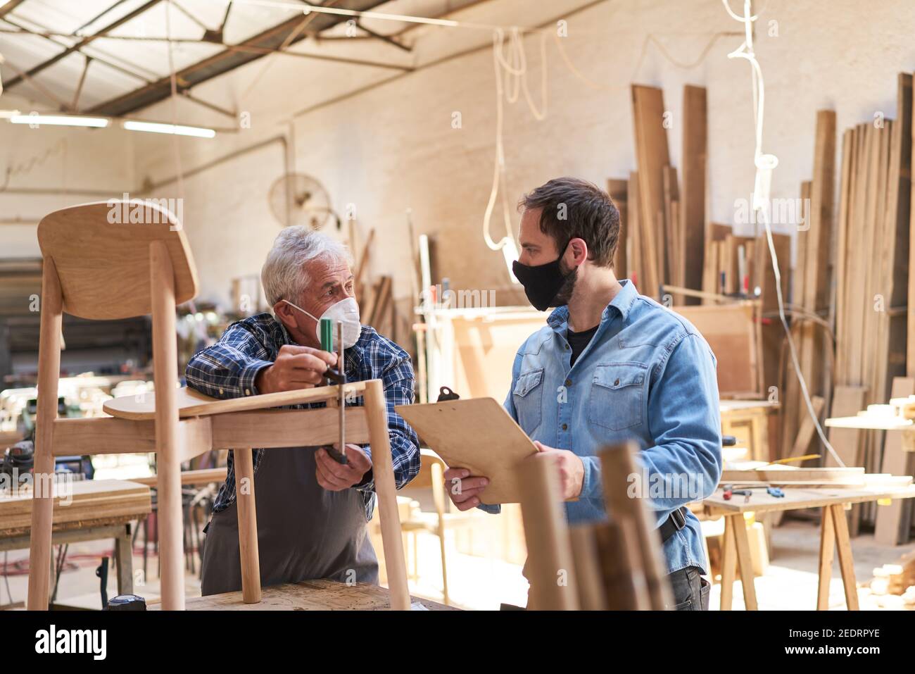 Senior Handwerker und Möbelbauer Lehrling mit Gesichtsmaske, weil Von Covid-19 Stockfoto