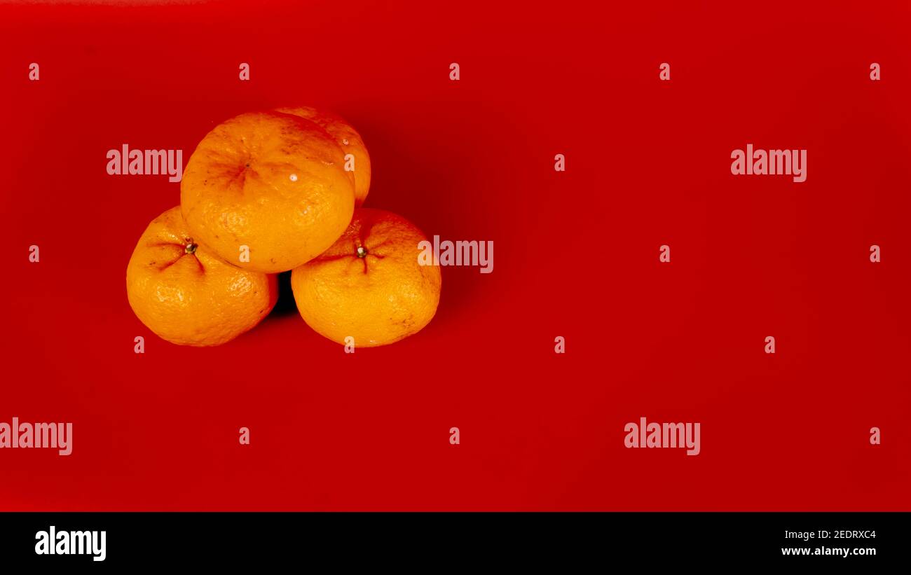 5 Mandarinorangen für die chinesische Neujahrfeier und Dekoration Auf rotem Hintergrund Stockfoto