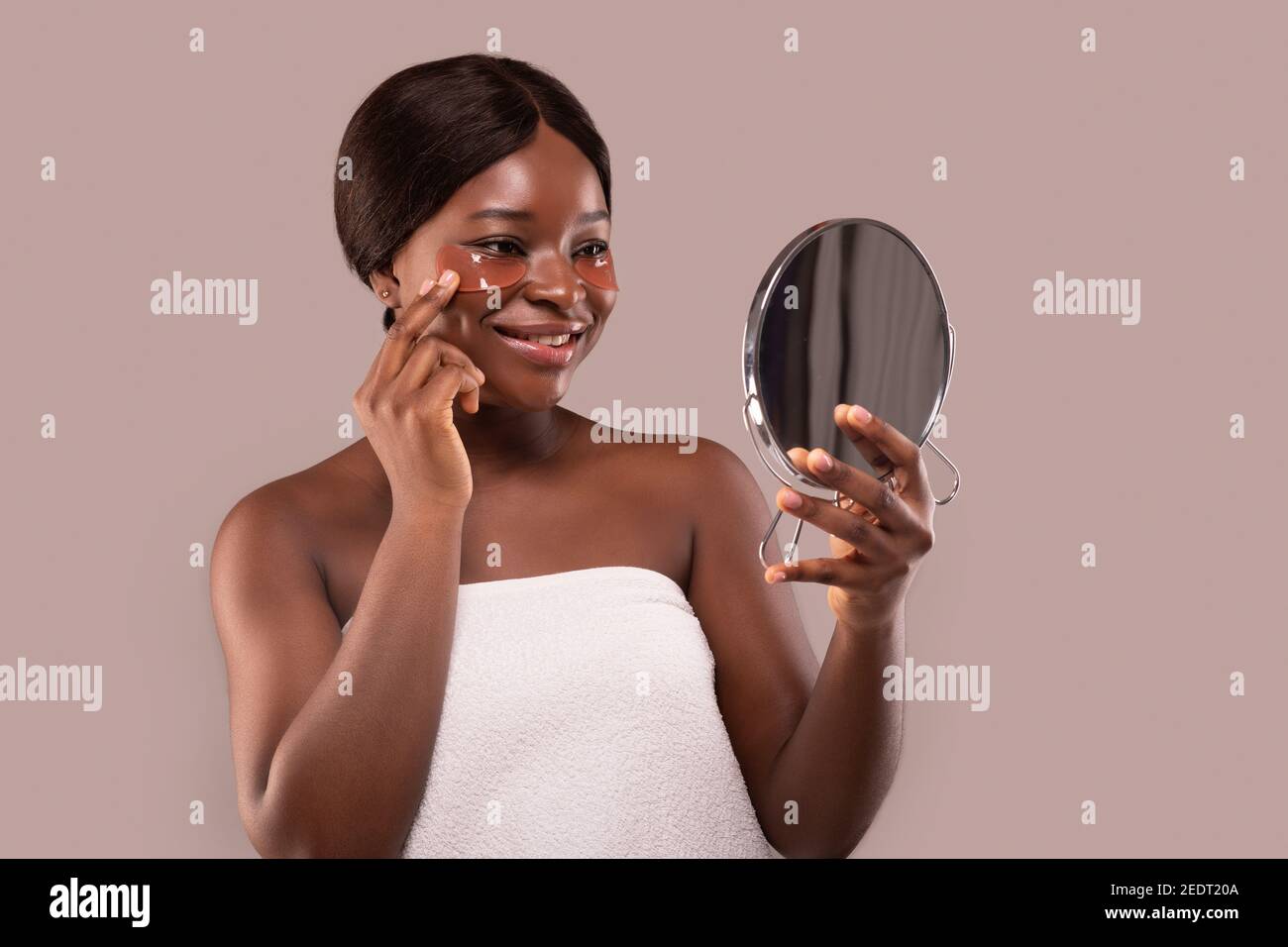 Schöne Schwarze Lady Halten Spiegel Und Auftragen Unter Augenaufnäher Maske Stockfoto