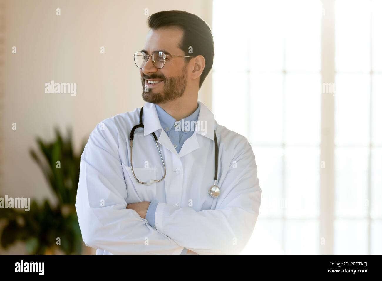 Lächelnd junge gut aussehende professionelle Arzt suchen in der Ferne. Stockfoto