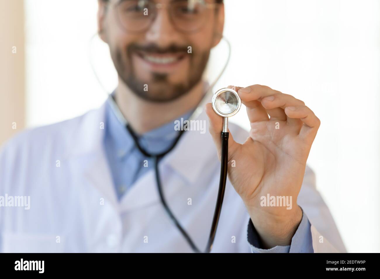 Nahaufnahme lächelnd junge gut aussehende männliche Arzt hält Stethoskop. Stockfoto