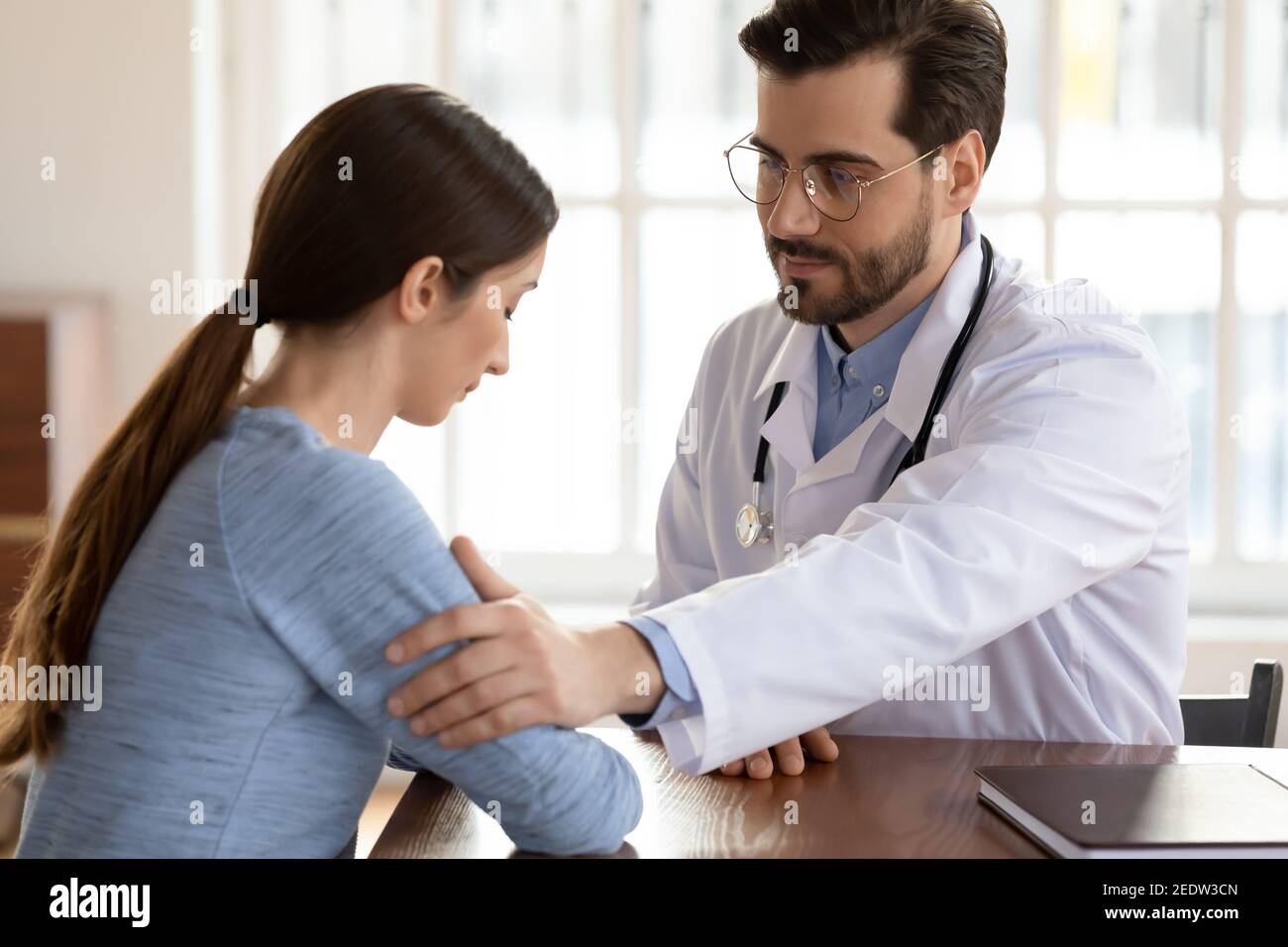 Mitfühlender freundlicher junger männlicher Arzt, der depressive Patienten unterstützt. Stockfoto