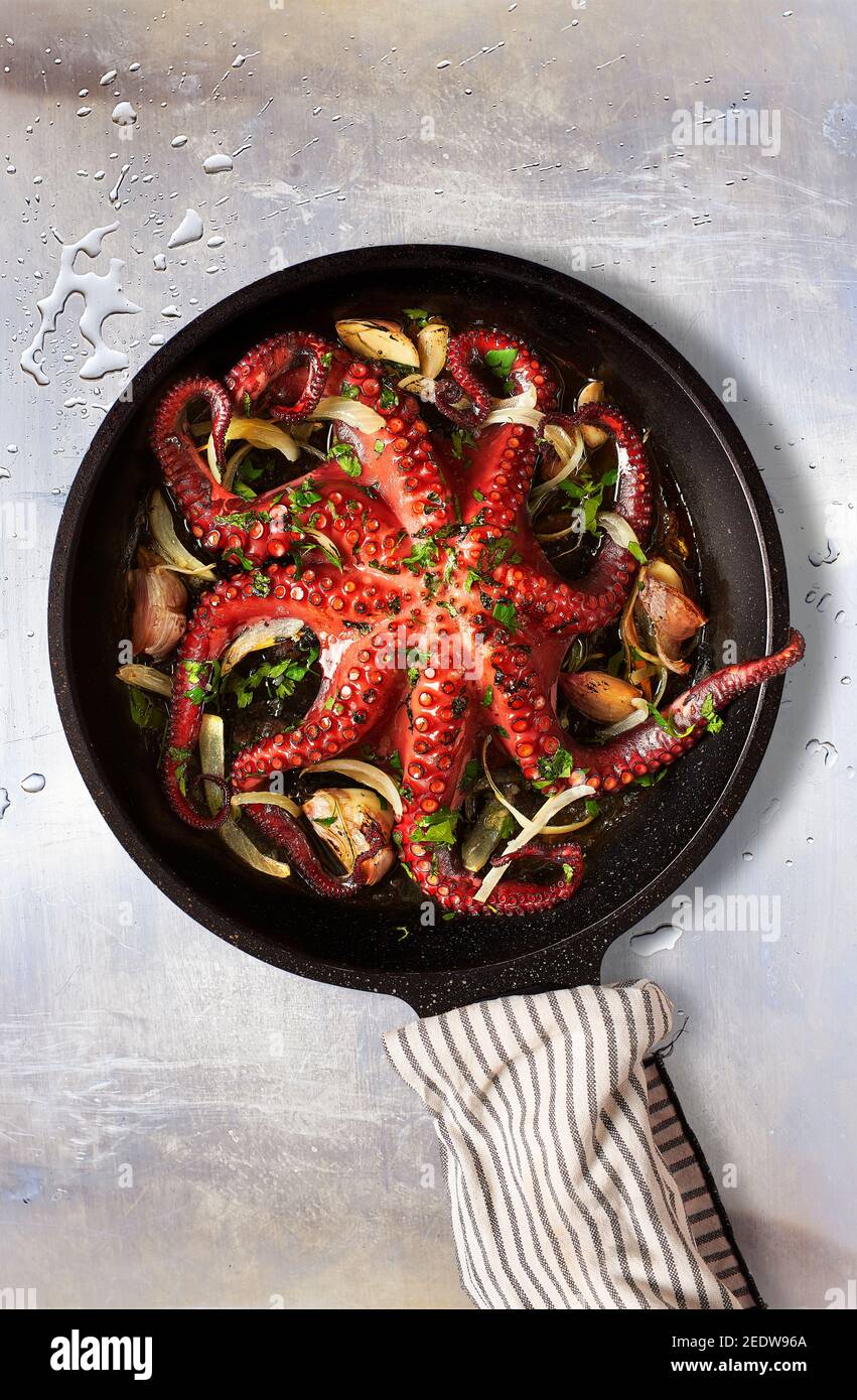 Octopus Lagareiro Stil gekleidet mit Zwiebeln und garlics Nelken auf einem gealterten Metalltisch. Portugiesische Küche. Stockfoto