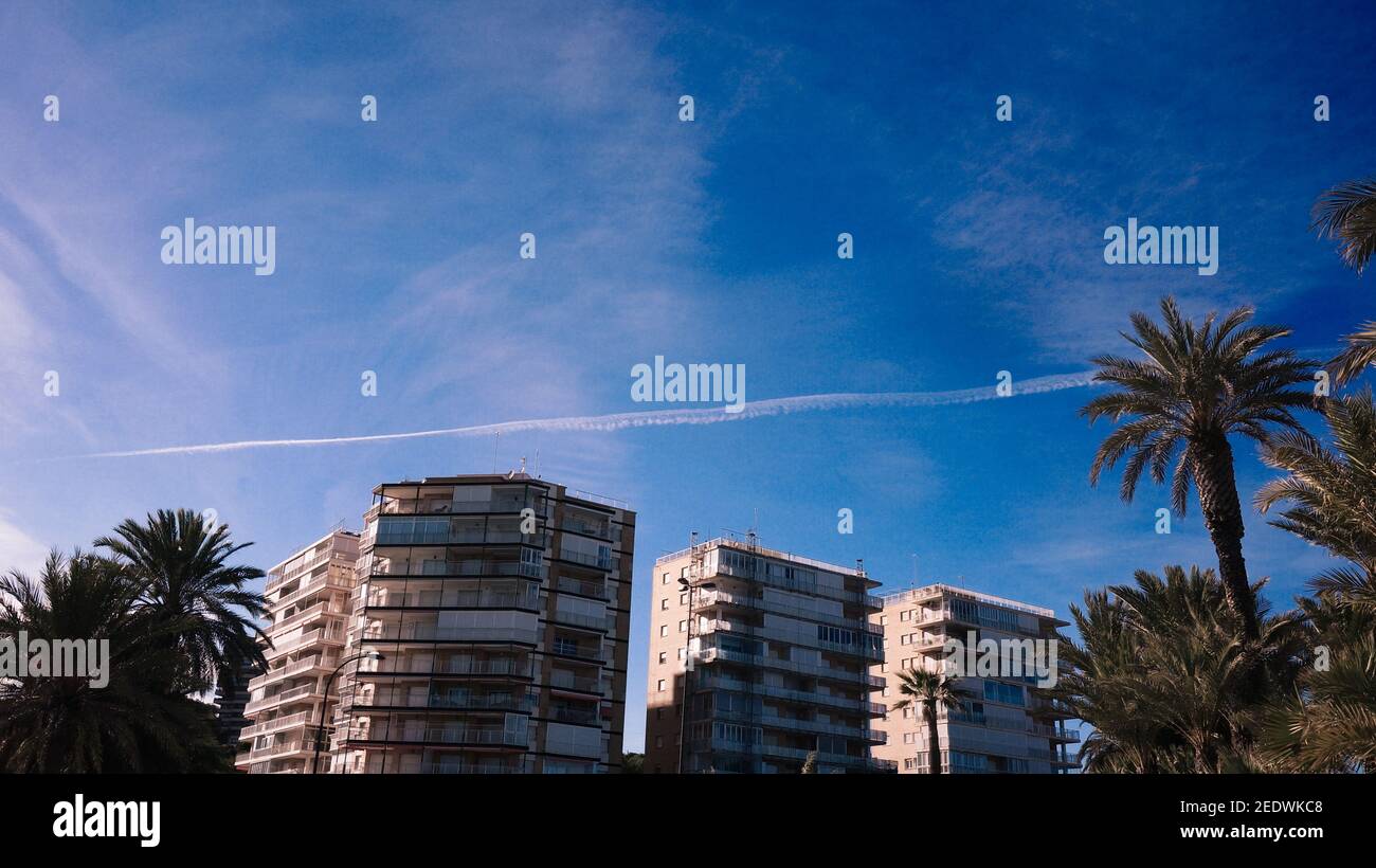 Chemtrails folgen am blauen Himmel über Häusern Stockfoto