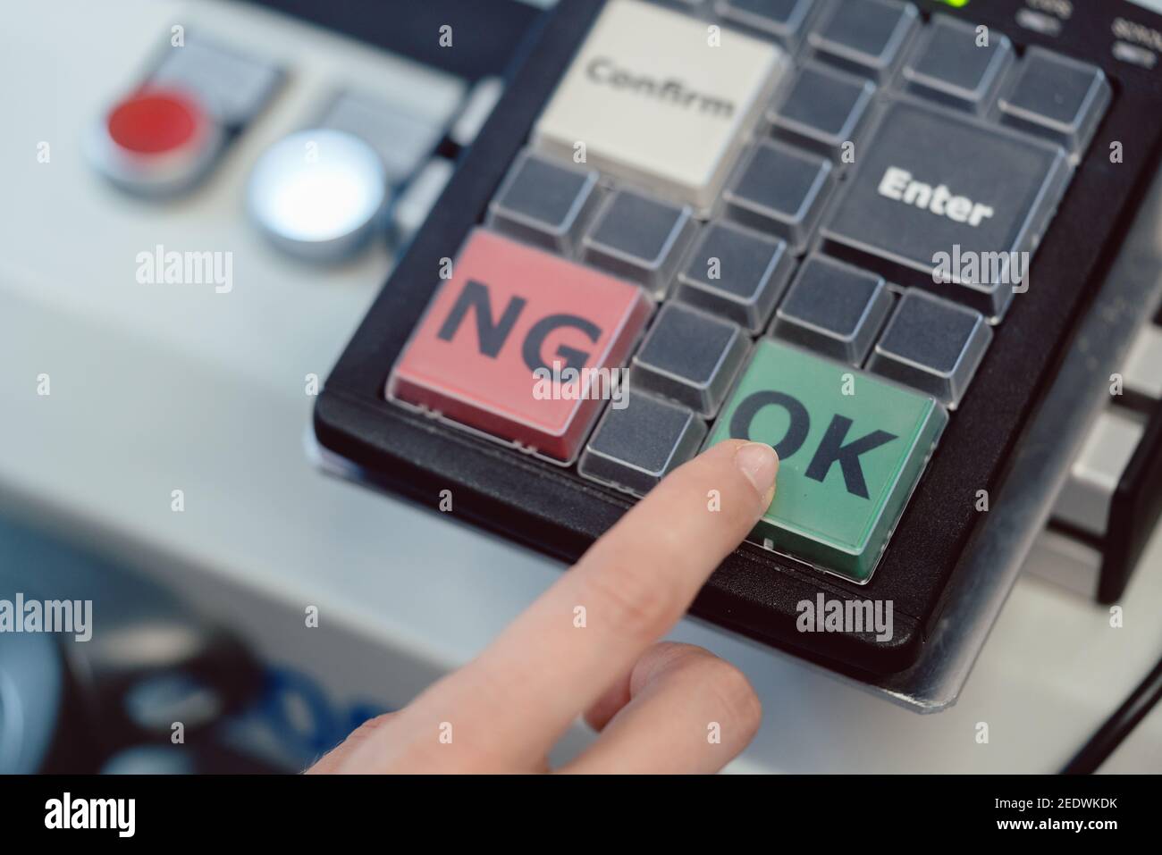 Fabrikarbeiter, der an einer Maschine die OK-Taste drückt Stockfoto