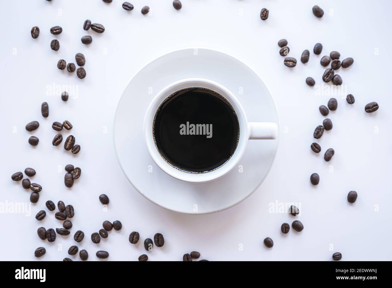 Flacher Lay von heißem Americano Kaffee in weißen Kaffeetasse Und Kaffeebohnen auf weißem Hintergrund mit Kopierplatz Stockfoto