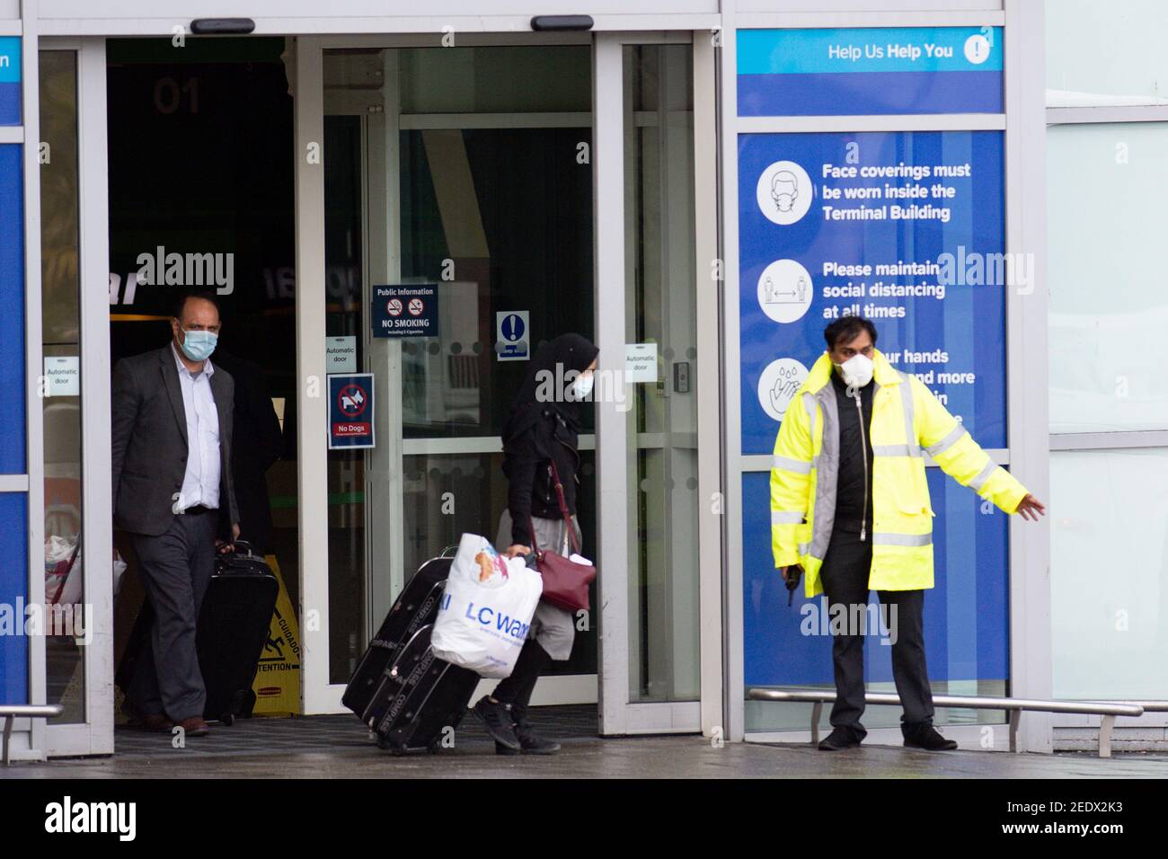 Nach der Landung in England verlassen zwei Passagiere den Flughafen Birmingham an Bord eines Busses. Neue Vorschriften, die jetzt in Kraft sind, verlangen, dass jeder, der sich vor kurzem an einem Ort mit hohem Risiko befindet, über einen bestimmten Hafen nach England einreist und ein Paket im Voraus gebucht hat, in einer der von der Regierung verwalteten Quarantäneeinrichtungen übernachtet. Bilddatum: Montag, 15. Februar 2021. Stockfoto