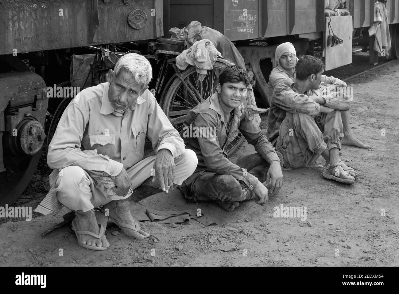 Arbeiter, die mit schweren Zementsäcken beschäftigt sind, genießen eine Pause neben der Eisenbahn in Mathura, Uttar Pradesh, Indien. Stockfoto