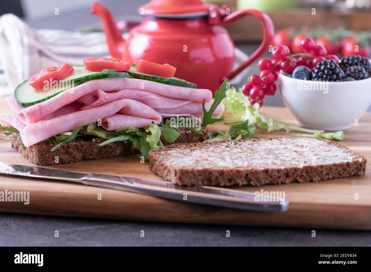 Frühstück mit offenem Gesicht Sandwich auf einem Küchentisch mit Teekanne Und frische Beeren Stockfoto