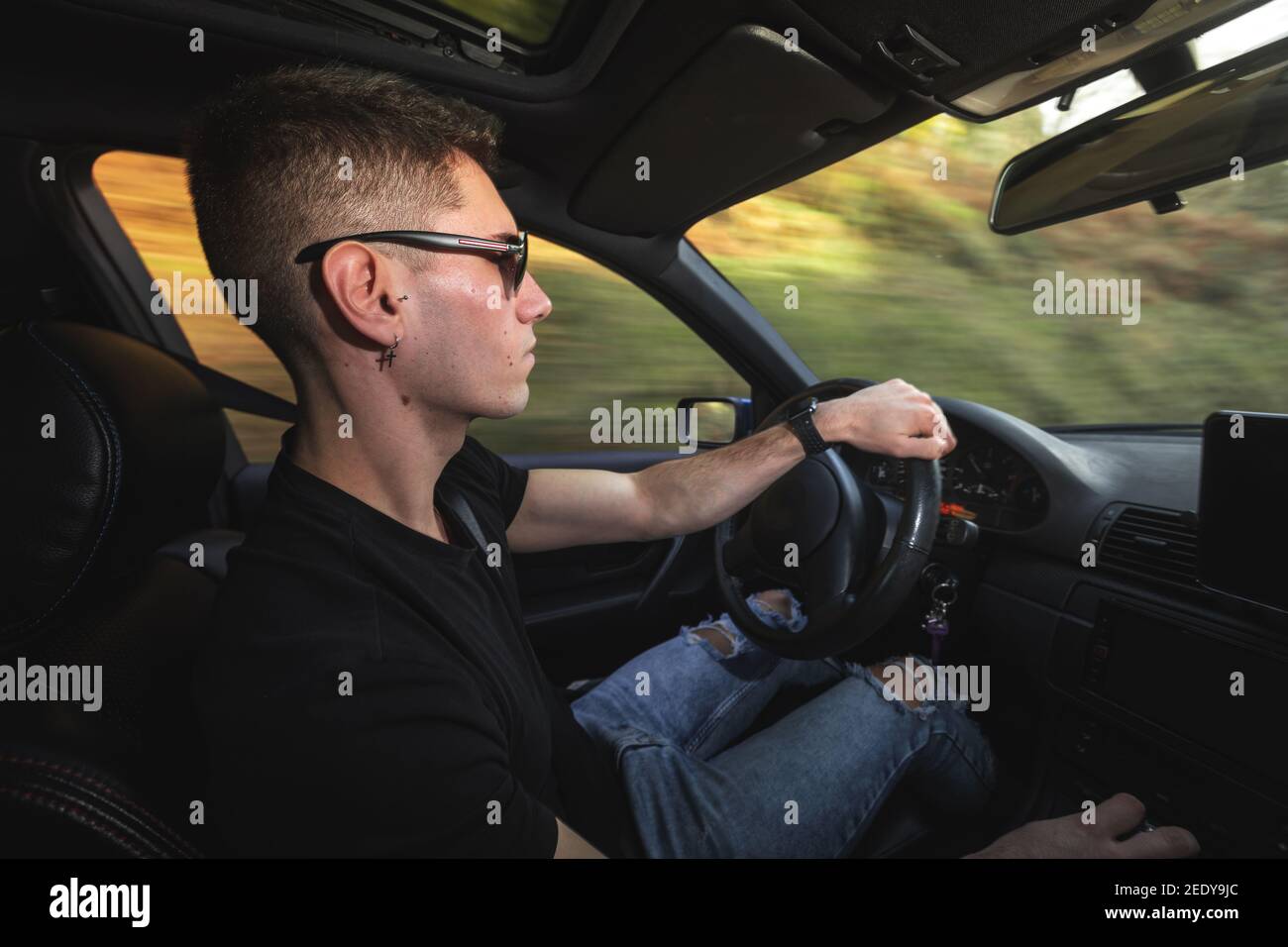 Junger Kaukasier, der einen Sportwagen fährt Stockfoto