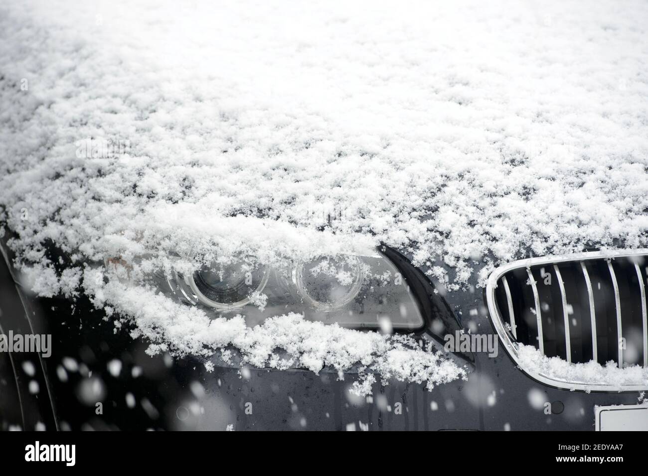 Schnee liegt auf der Motorhaube eines BMW Autos. Stockfoto