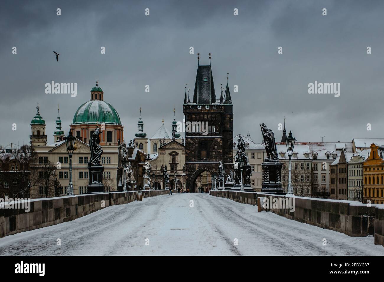 Winteransicht der Karlsbrücke, Altstädter Brückenturm mit Schnee bedeckt, Prag, Tschechische Republik. Menschen, die im kalten Winter durch die Stadt wandern Stockfoto
