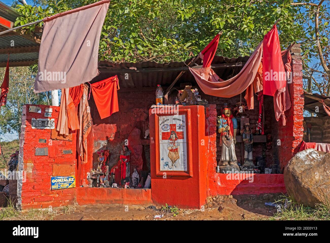 Traditioneller roter Schrein am Straßenrand zum volksheiligen Gauchito Gil / Little Gaucho Gil, argentinischer schutzpatron der Reisenden, Cowboys und Gauchos, Argentinien Stockfoto