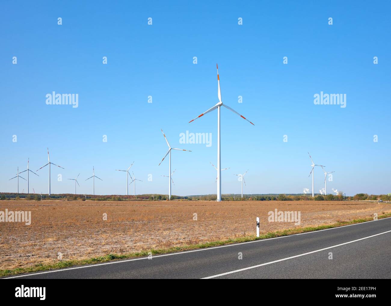Bild von einem Windturbinenpark an einer Straße gegen den blauen Himmel. Stockfoto