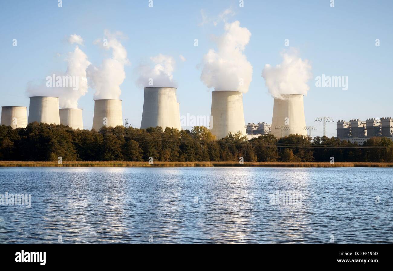 Kraftwerk mit rauchenden Kaminen am See bei Sonnenuntergang. Stockfoto