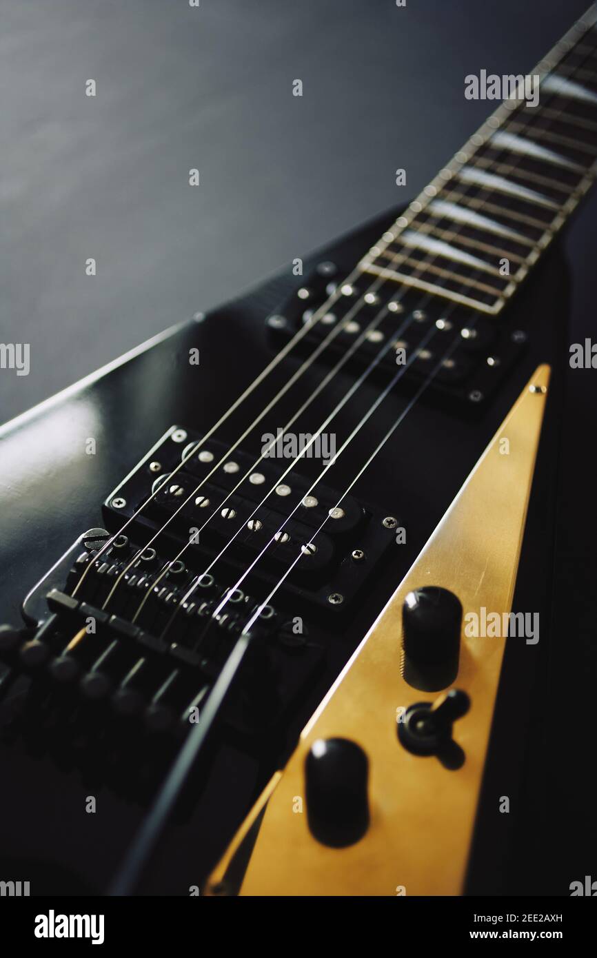 Crop Soft Fokus Schuss von schwarzen V-Form E-Gitarre Auf dunklem Grunge-Hintergrund Stockfoto