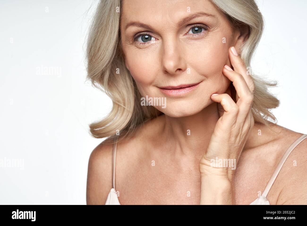 50s Frau mittleren Alters berührt Gesichtshaut Blick auf die Kamera. Anti-Age-Hautpflege. Stockfoto