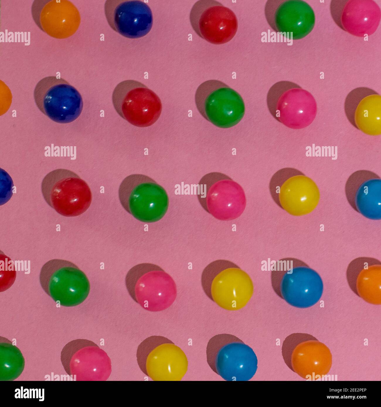Candy ist auf buntem Papier angeordnet, wodurch sich wiederholende Muster entstehen. Serie. Stockfoto