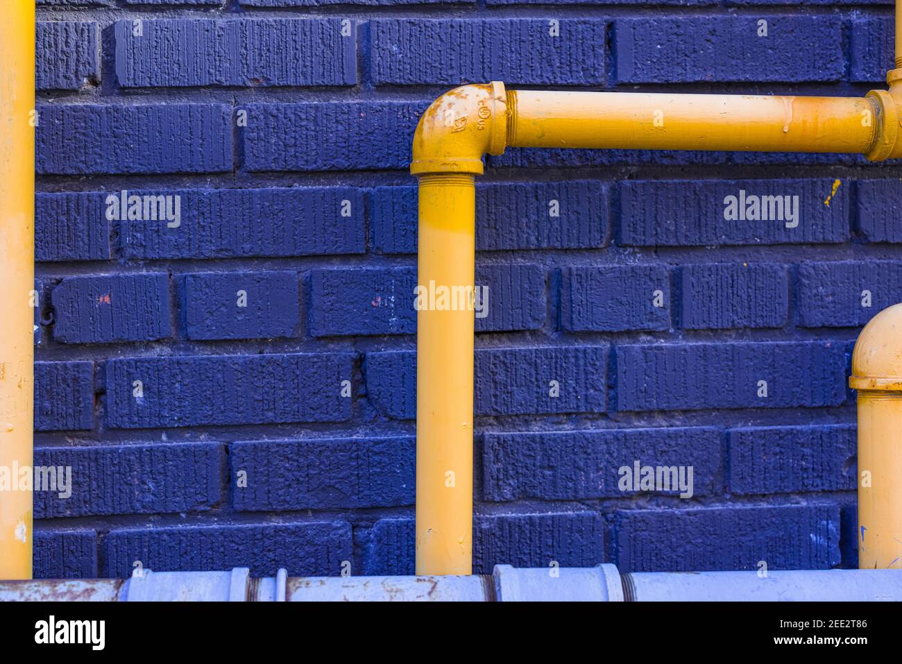 Gelbe Stahlrohre Blaue Ziegelwand Stockfoto