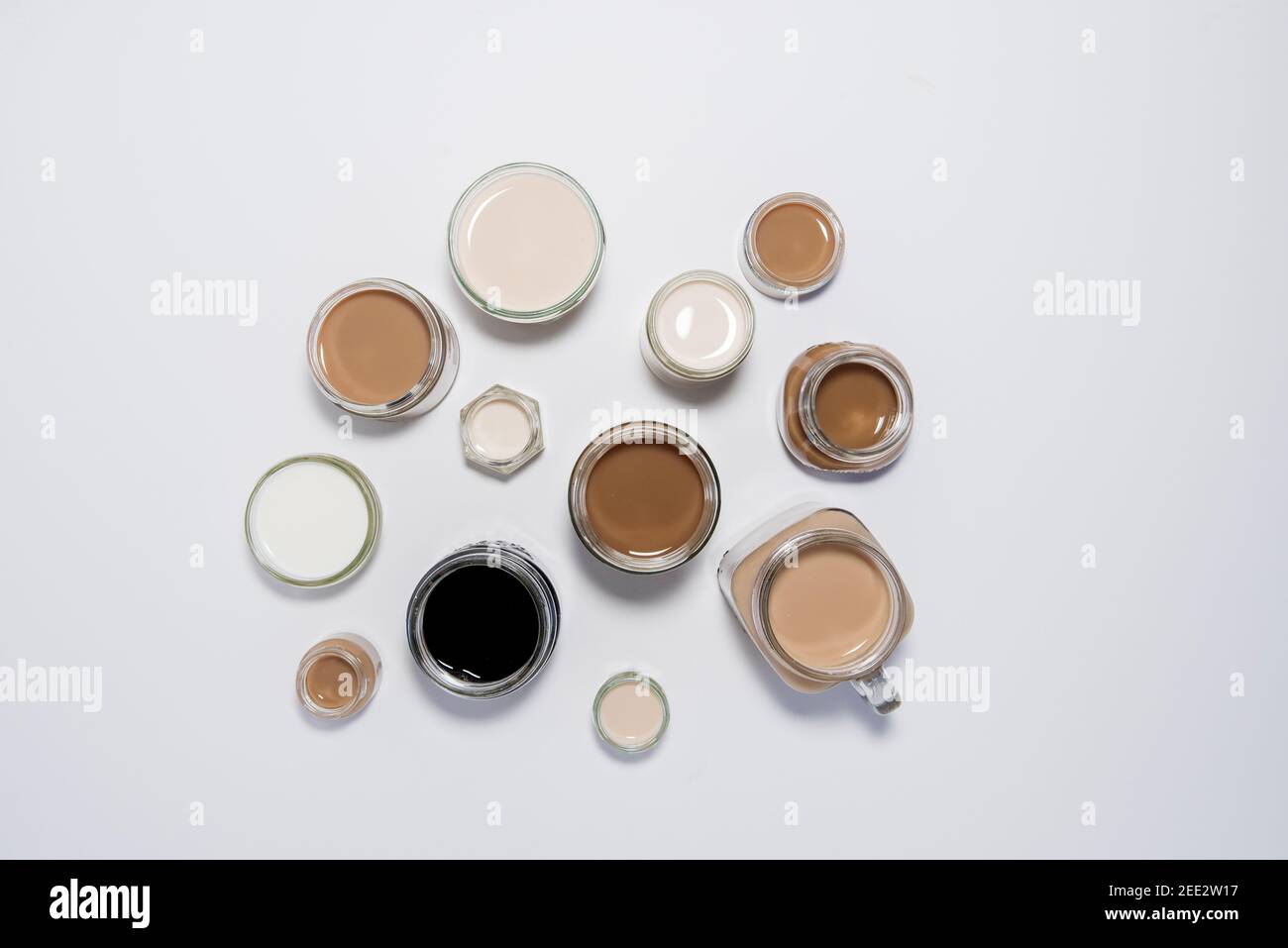 Eine konzeptuelle Aufnahme mit Milch/Tee/Kaffee in Tassen, die in einer Weise angeordnet sind, die einen Farbverlauf erzeugt. Kaffeetönen. Stockfoto