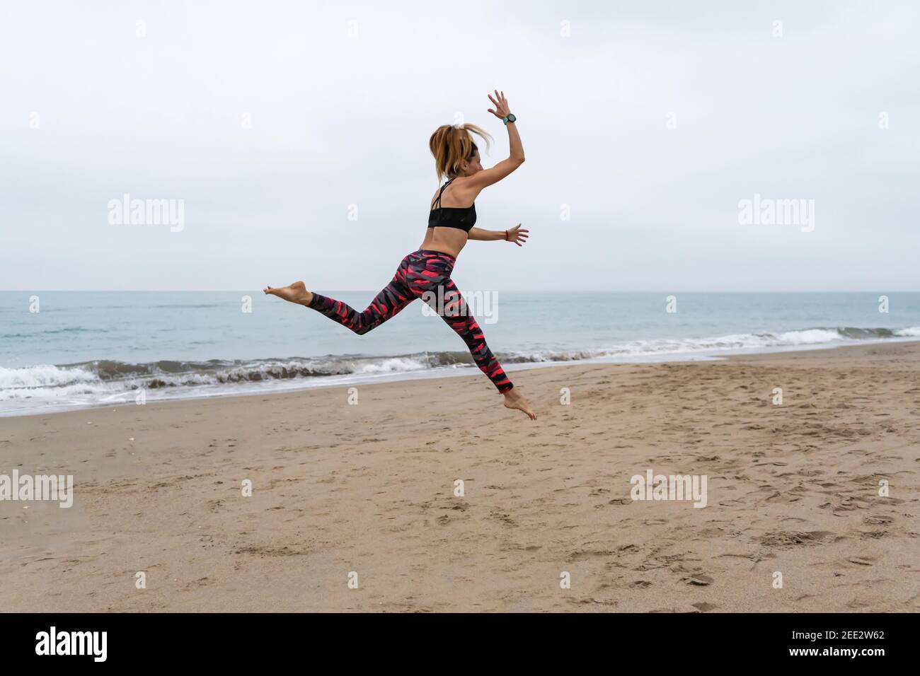 Fitness athletische Frau springen am Strand während des Trainings.Konzept von Glück, Yoga und Training Lebensstil. Stockfoto