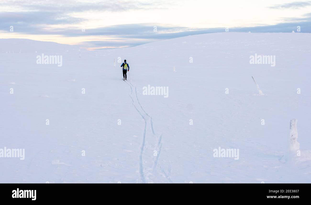 Ein Mann klettert den Hang eines schneebedeckten Berges in Lappland Stockfoto