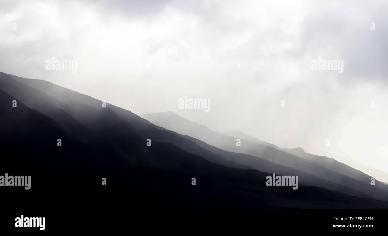 Schwarz-weiße Bergridgelines unter Wolken führen über den unteren Bildrand für einen dramatischen Hintergrund. Stockfoto