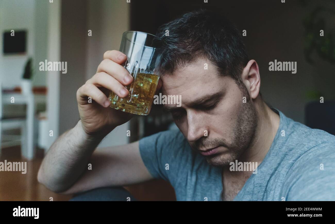 Erschöpfter betrunkener Mann mit Glas Whisky. Alkoholismus Konzept. Stockfoto