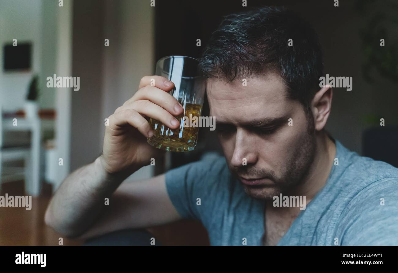 Erschöpfter betrunkener Mann mit Glas Whisky. Alkoholismus Konzept. Stockfoto