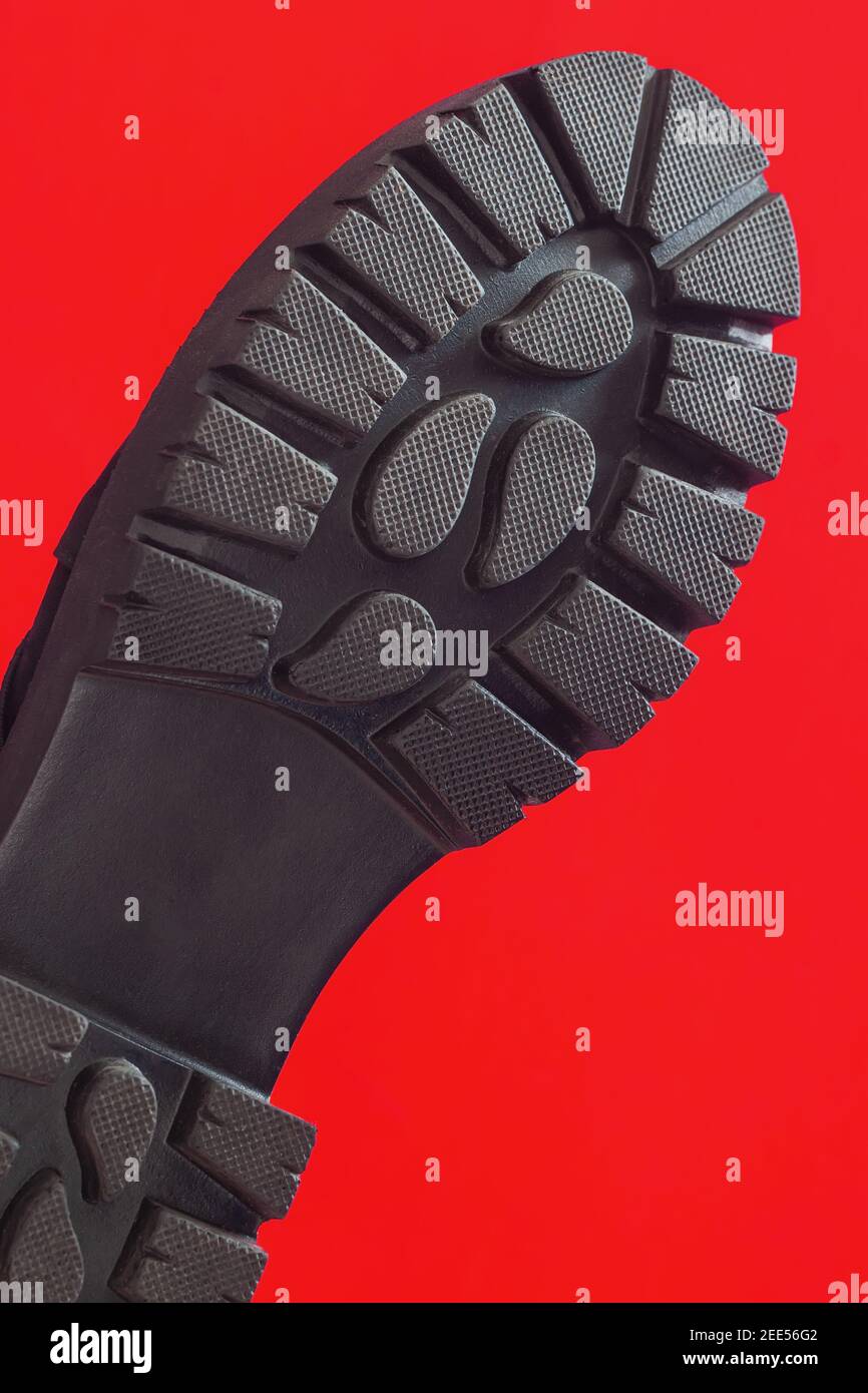 Schwarze Schuhsohle in Nahaufnahme auf rotem vertikalem Hintergrund Stockfoto
