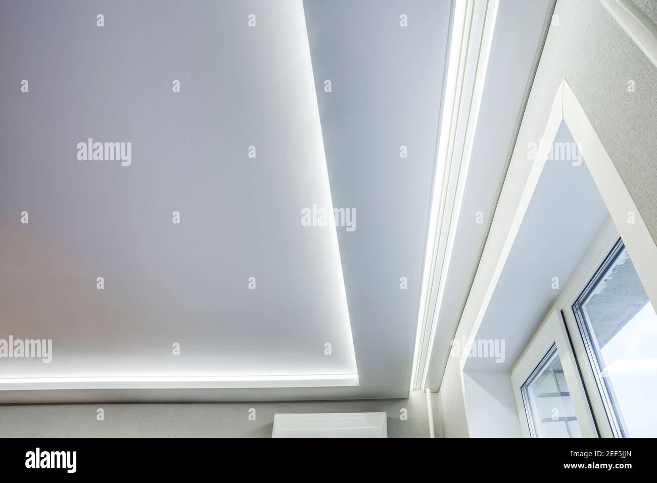 Abgehängte Decke mit Halogenstrahlern und Trockenmauerkonstruktion im leeren Raum in Wohnung oder Haus. Stretchdecke weiß und komplex. Stockfoto