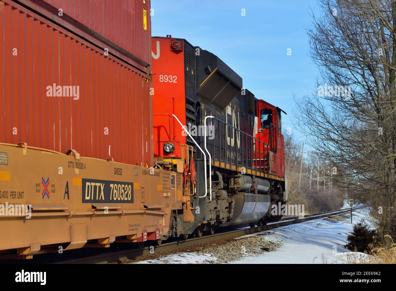 Barrington, Illinois, USA. Canadian National Railway Lokomotive führt einen Güterzug durch ein Baum- und Fabrik-lined rechts-of-way. Stockfoto