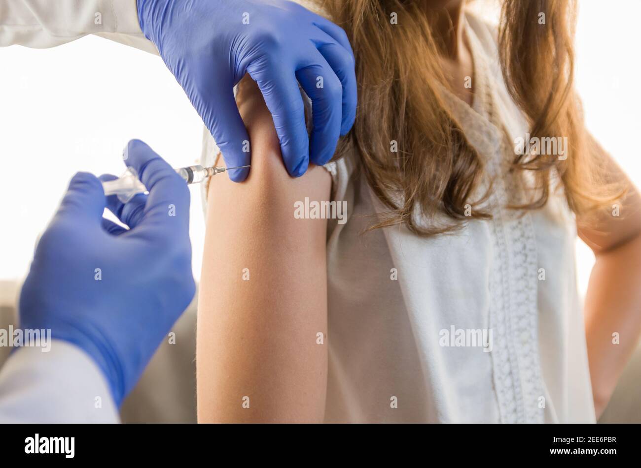 Nahaufnahme Arzt hält Spritze und mit Baumwolle vor der Injektion an den Patienten in medizinische Maske. Covid-19 oder Coronavirus-Impfstoff. Stockfoto