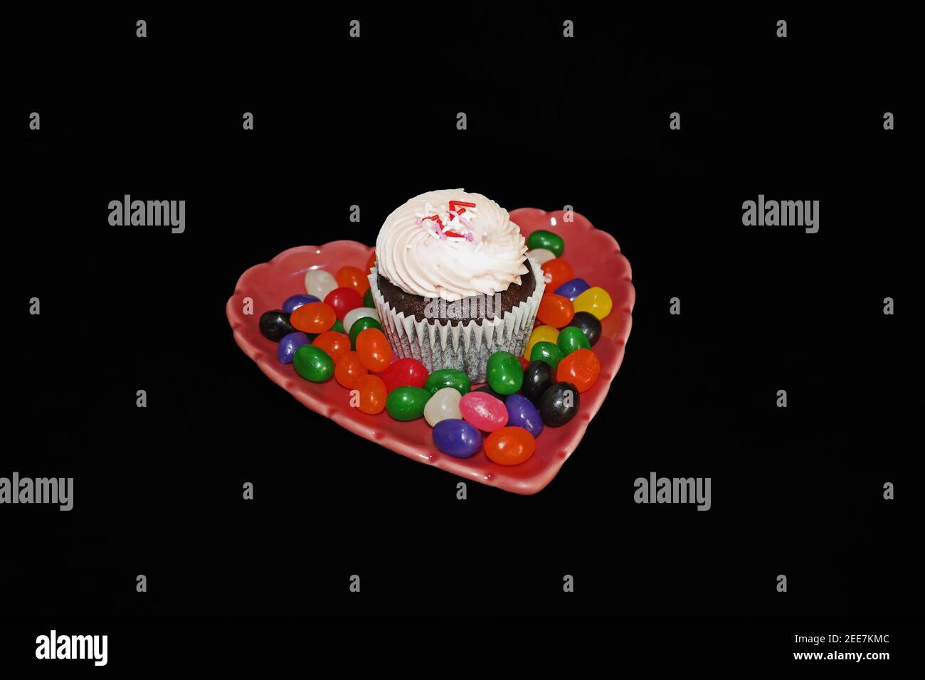 Erdbeer-Cupcake auf herzförmiger Platte mit Süßigkeiten Stockfoto