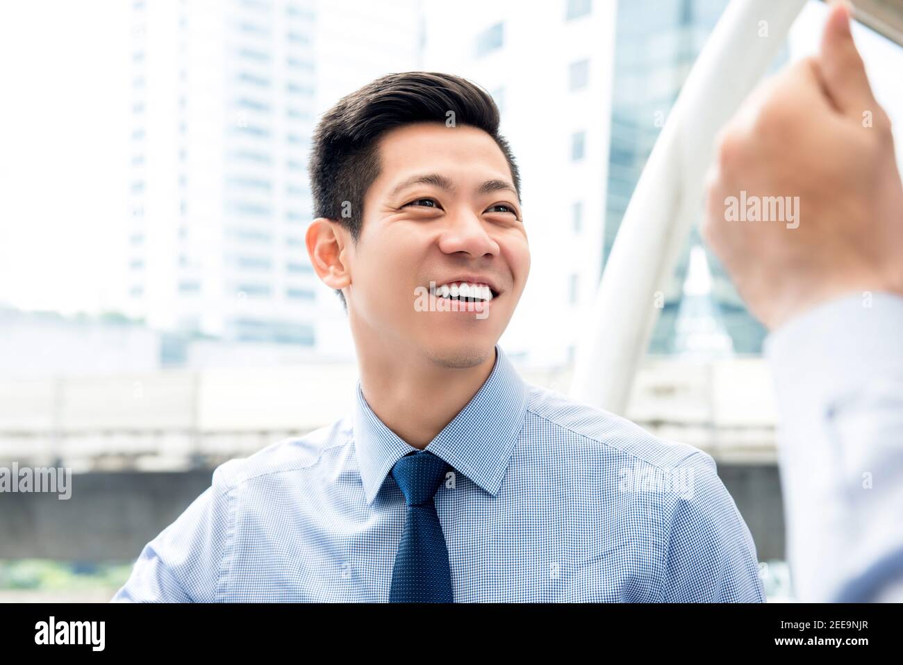 Lächelnd freundlich gut aussehende asiatische Geschäftsmann im Gespräch mit Kollegen im Freien in Die Stadt Stockfoto