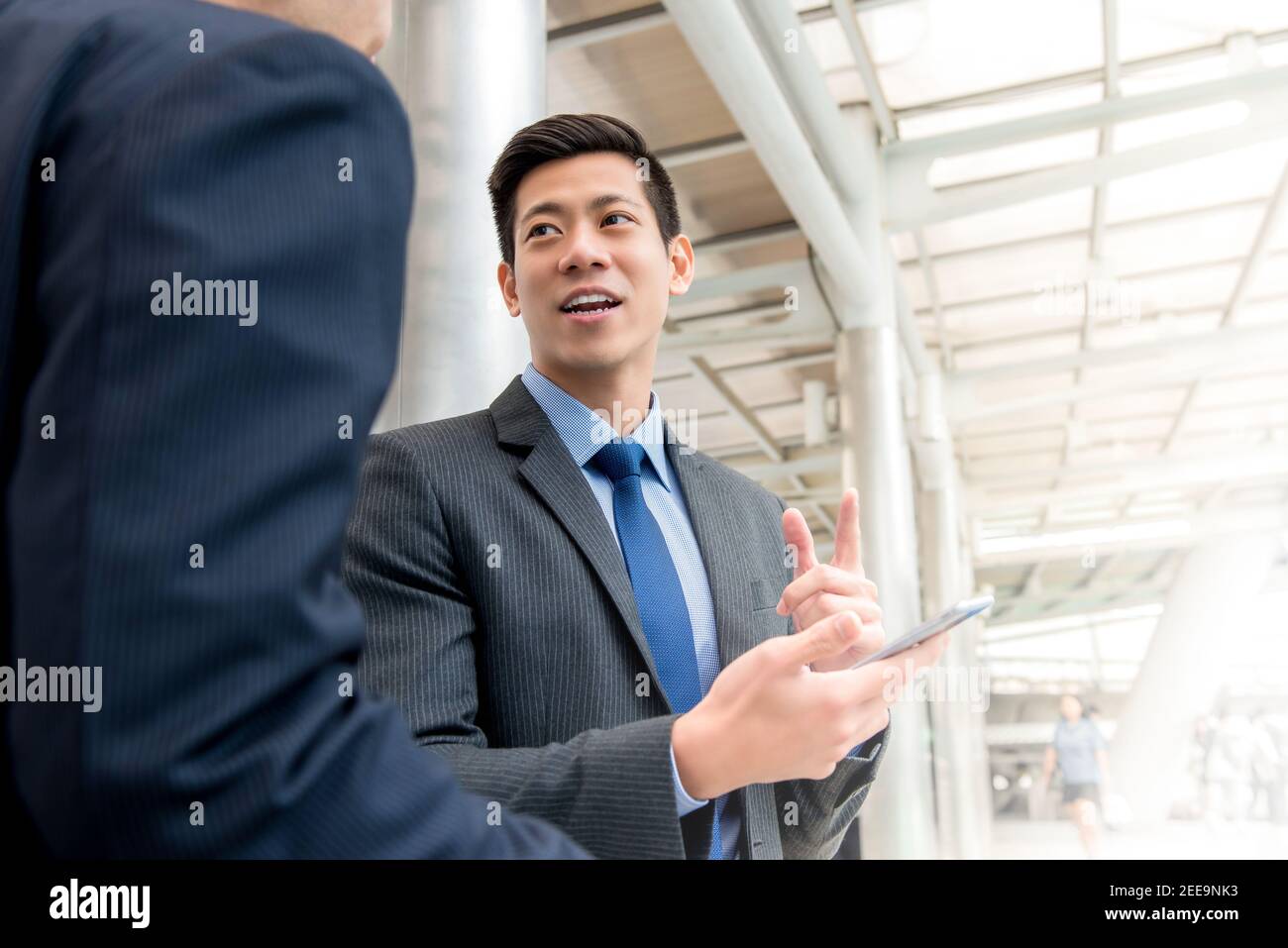 Asiatische chinesische Geschäftsmann im Gespräch mit seinem Kollegen im Freien bedeckt Gehweg in der Stadt Stockfoto