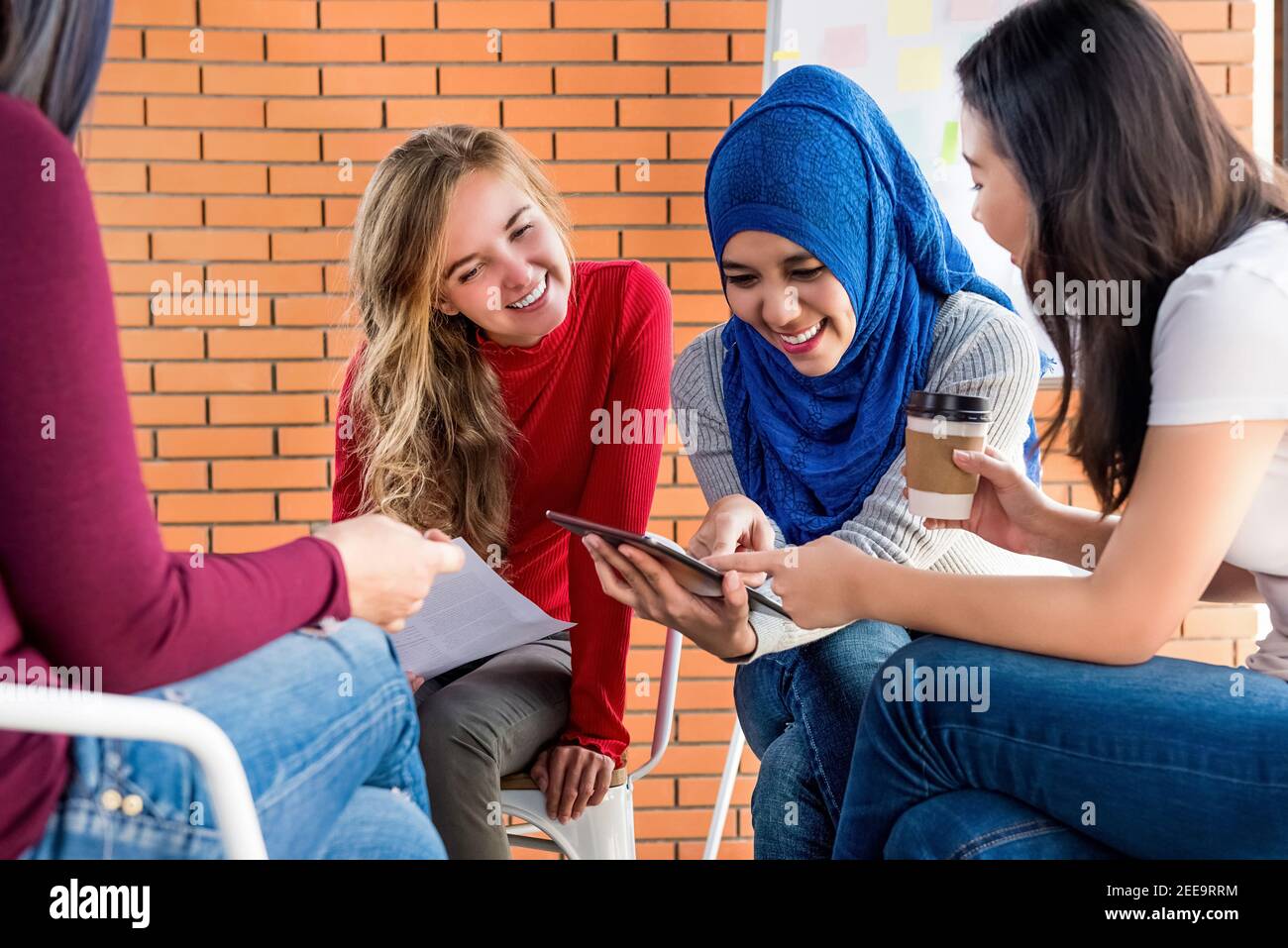 Multiethnische Frauen in bunten Freizeitkleidung Blick auf Tablet-Computer Gemeinsam in Gruppenbesprechung Stockfoto