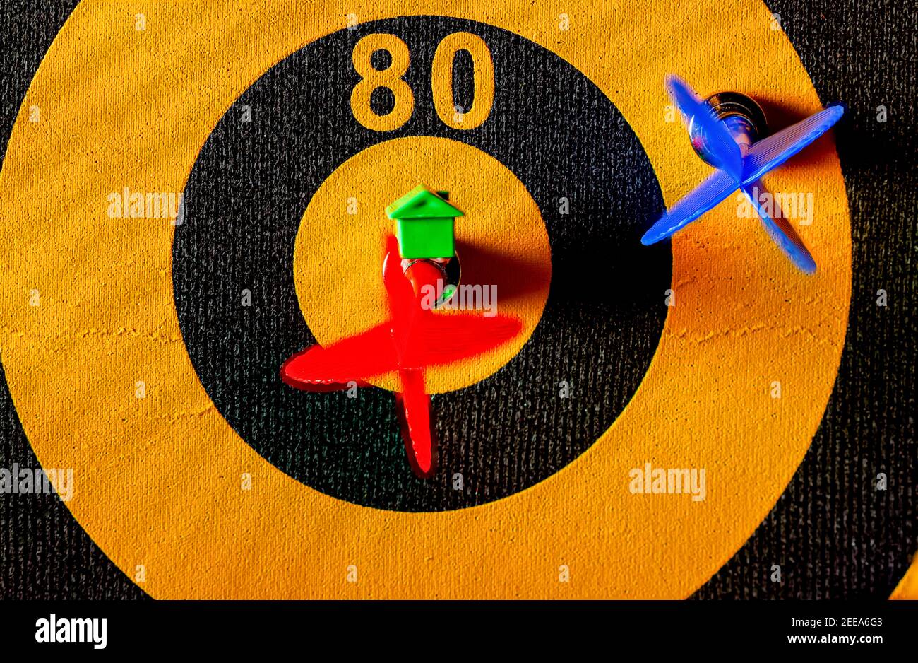 Ein Dartboard mit einem Pfeil, der das Bullseye trifft. Es gibt ein kleines Haus Symbol auf diesem Pfeil. Ein vielseitiges Image für Wettbewerb, Immobilien, Hou Stockfoto