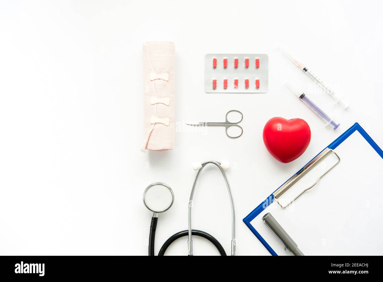 Medizinische Instrumente mit roter Herzform auf weißem Hintergrund, Draufsicht mit Kopierraum Stockfoto