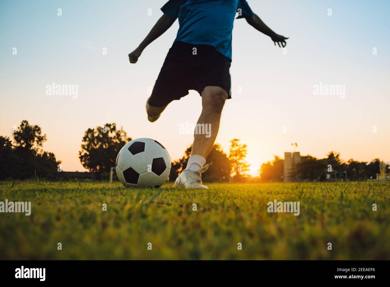 Action-Sport im Freien einer Gruppe von Kindern, die Spaß beim Fußball spielen Fußball für die Ausübung in der Gemeinde ländlichen Raum unter der Dämmerung Sonnenuntergang. Stockfoto