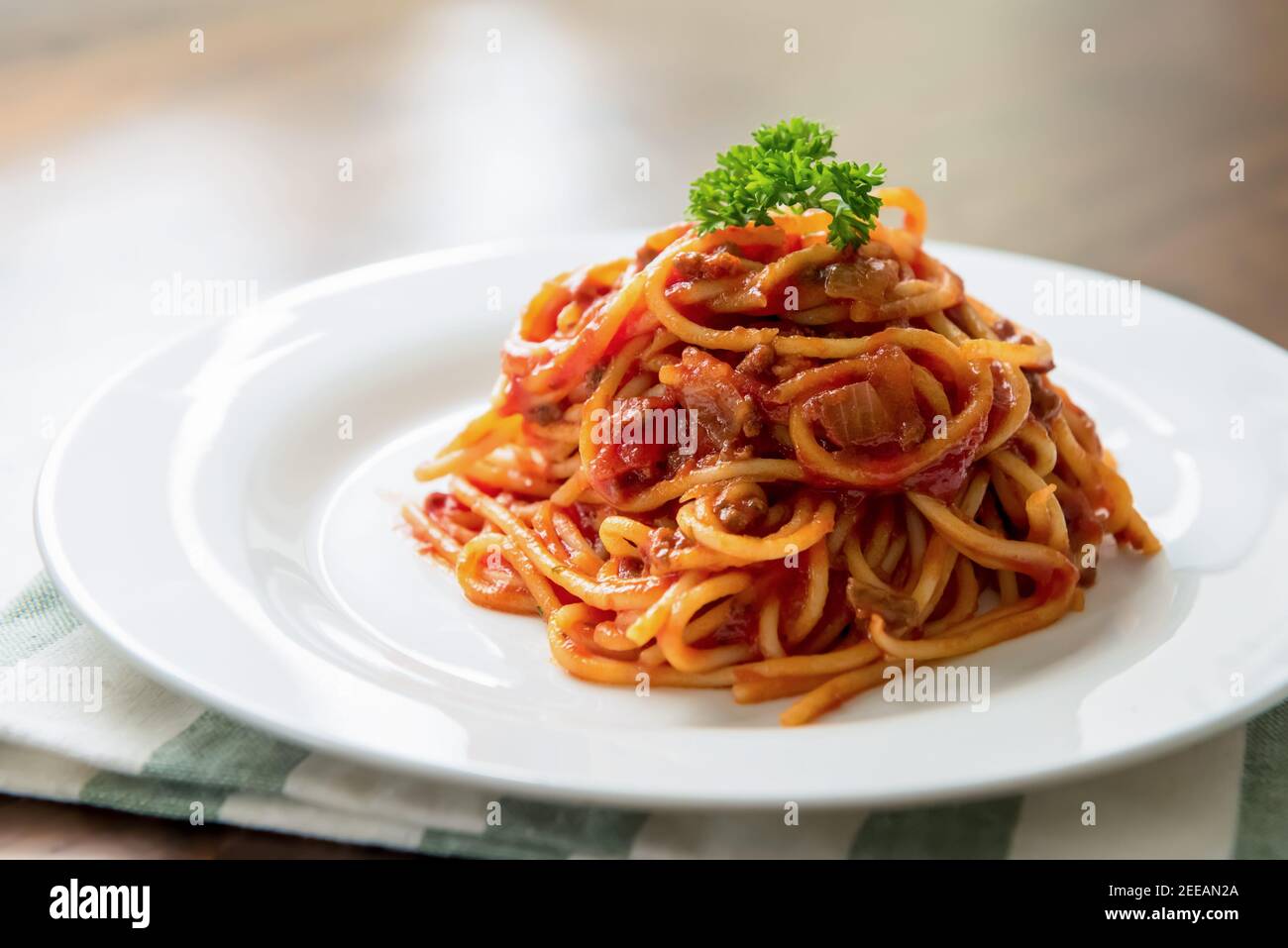 Köstliche italienische Bolognese Fleisch Spaghetti mit Petersilie auf der Oberseite dekoriert In weißer Schale am Tisch Stockfoto