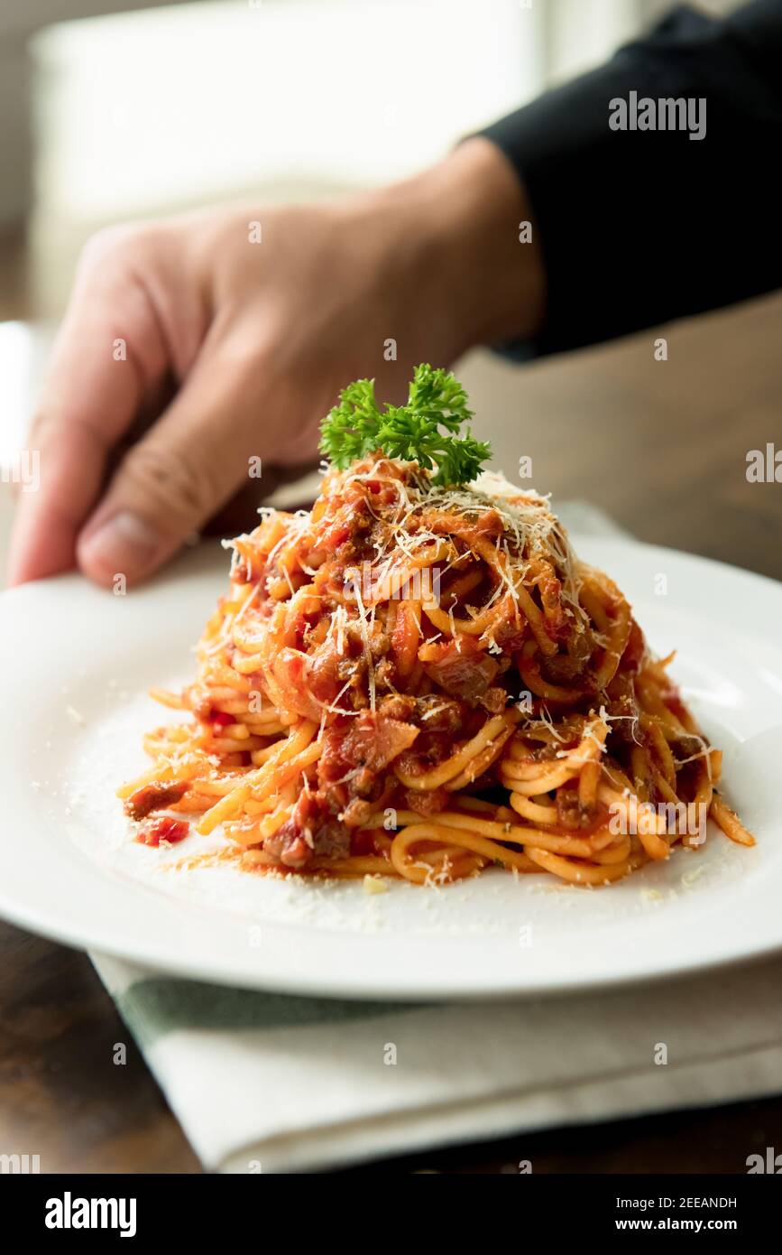 Köstliche italienische Bolognese Fleisch Spaghetti mit Parmesan und Petersilie Oben in weißer Schale am Tisch Stockfoto