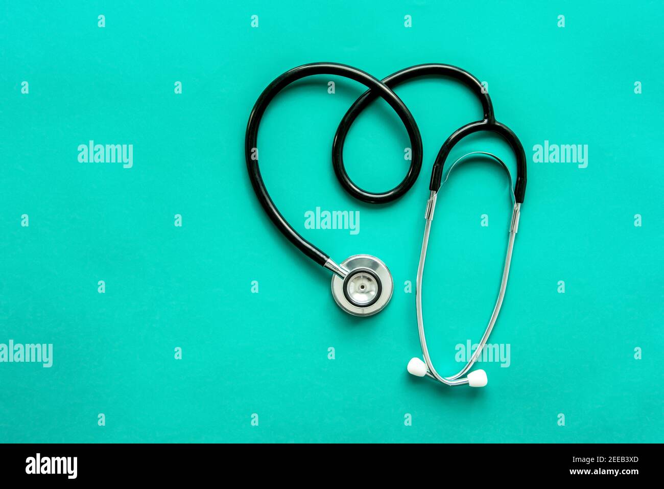 Stethoskop, medizinisches Instrument, in Herzform auf hellgrünem Hintergrund Stockfoto